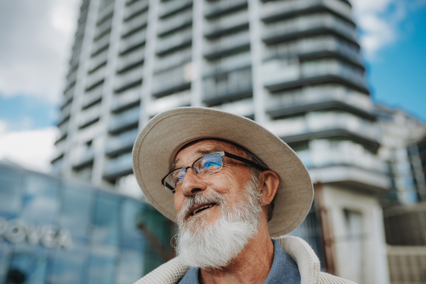 Confident senior man smiling in front of modern high-rise building