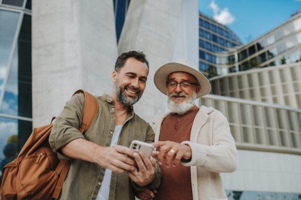 Father showing odler son something in smartphone, sharing a joyful moment outdoors