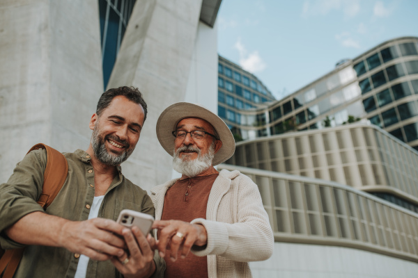 Father showing odler son something in smartphone, sharing a joyful moment outdoors