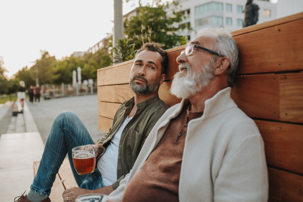 Father and son enjoying beer together outdoors. Fathers day concept.