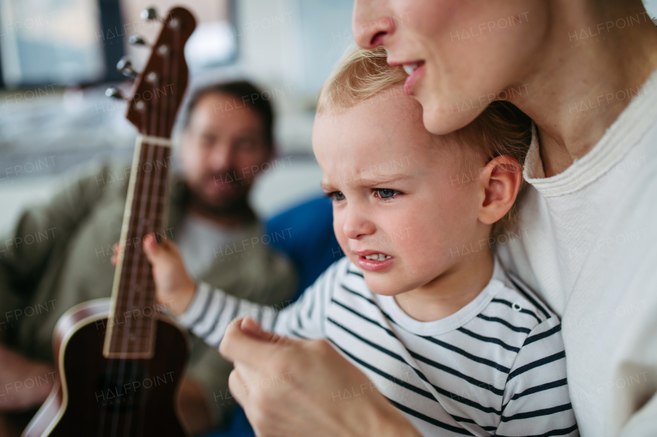 Little boy holding guitar, learning how to play.