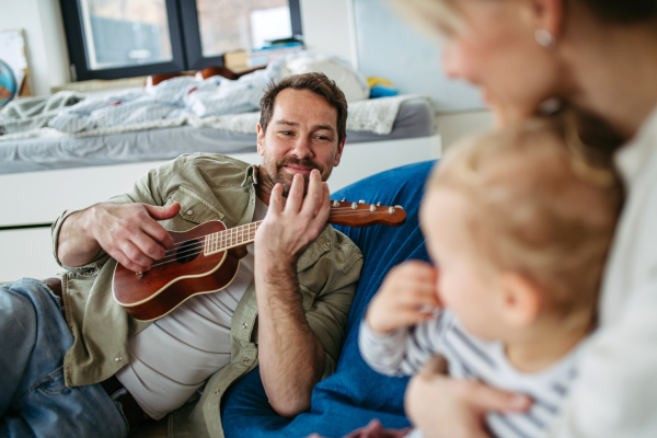 Family bonding moment. Father playing guitar for his wife and child.
