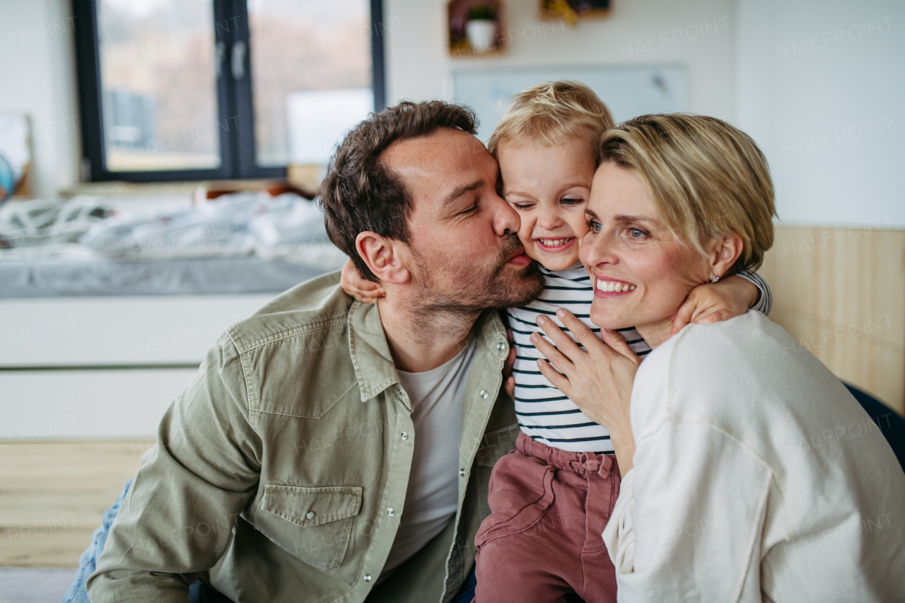Parents spending time with little son, kissing him on cheek.
