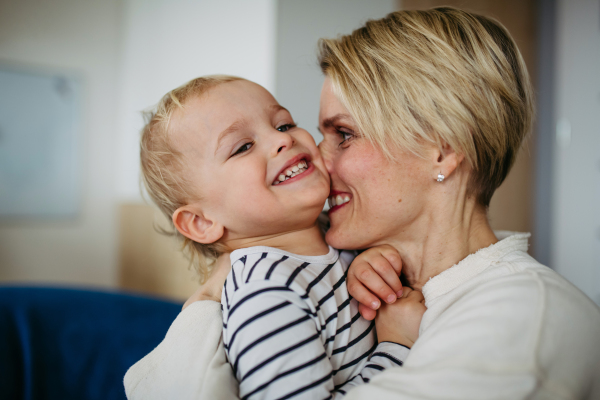 Beautiful mother hugging and kissing little young son.