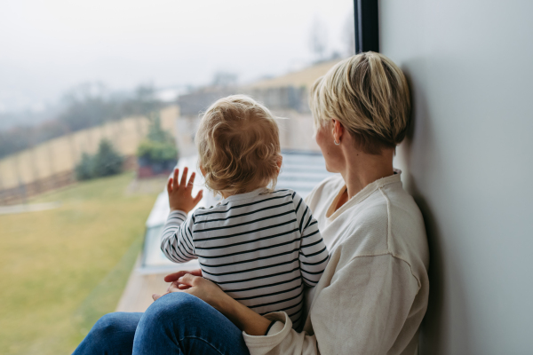 Boy and mother looking out of window, admiring nature.