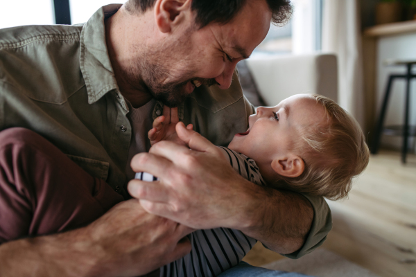 Mature father playing with little young son, holding him.
