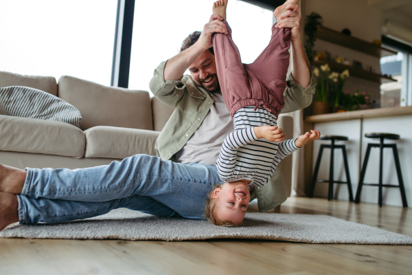 Playful father holding little son upside down, laughing.