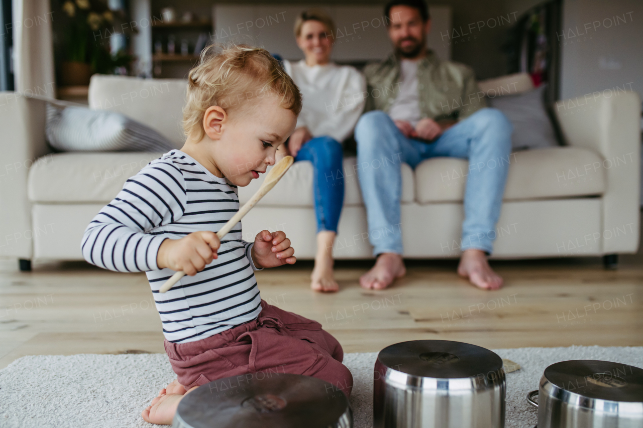 Little toddler boy playing drums on kitchen pots.