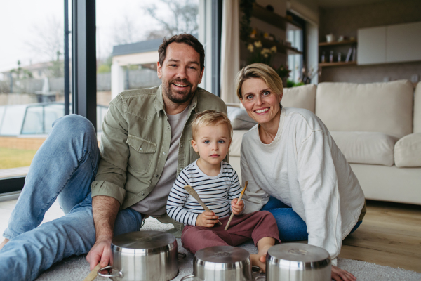 Parents and little toddler son playing drums on kitchen pots.