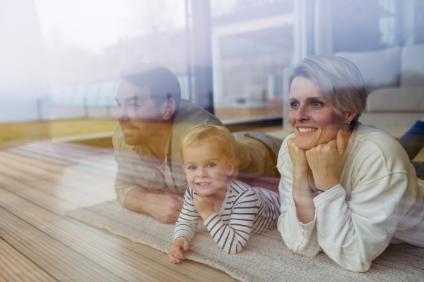 Parents and little boy looking out of window, lying on floor.