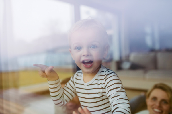 Cute boy looking out of window and laughing.