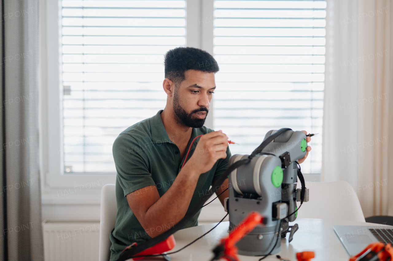 Engineering student assembling and coding a robotic arm at home as part of a robotics project.
