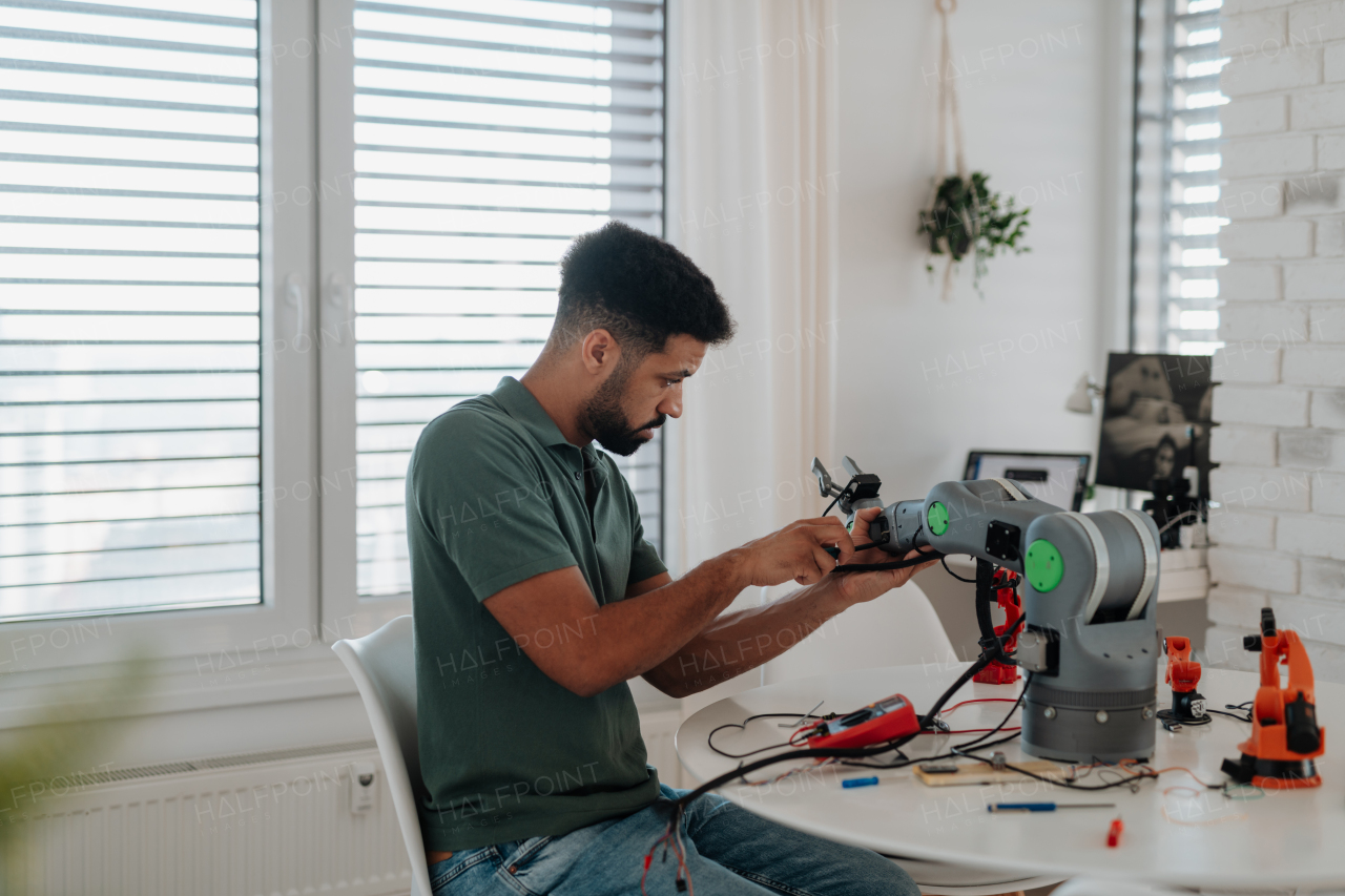 Young engineer building and programming a robotic arm at home. Robotics concept.