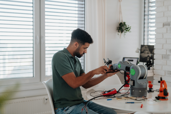 Young engineer building and programming a robotic arm at home. Robotics concept.
