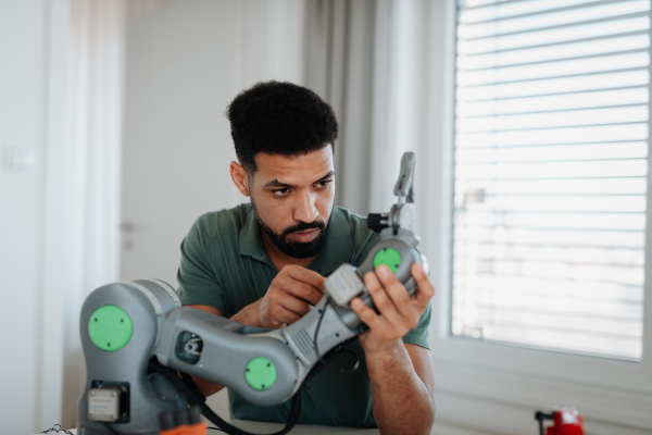 Young engineer building and programming a robotic arm at home. Robotics concept.