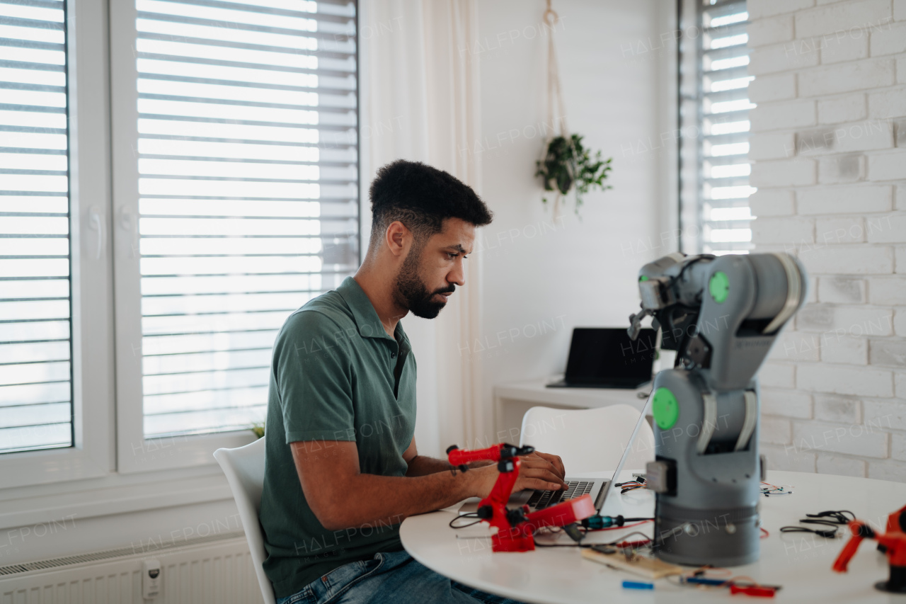 Side view of engineer building and programming a robotic arm at home. Robotics concept.