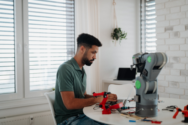 Side view of engineer building and programming a robotic arm at home. Robotics concept.