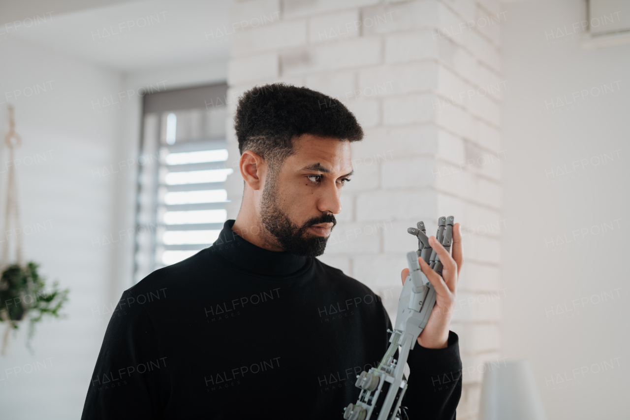 Portrait of young engineer holding robotic arm. Robotics concept.