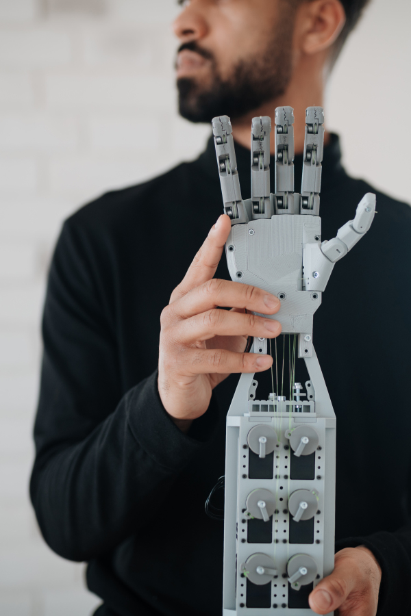 Portrait of young engineer holding robotic arm. Robotics concept.