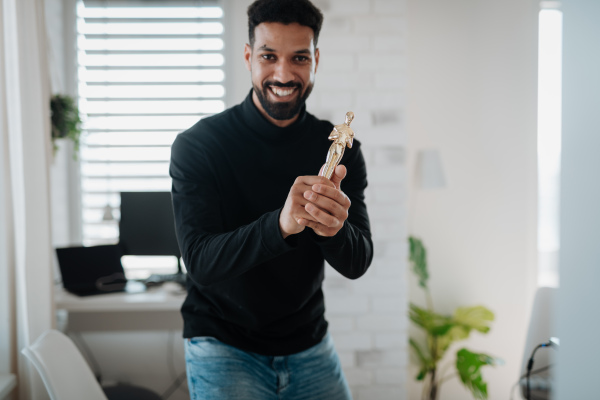 Happy man proudly holding a trophy at home