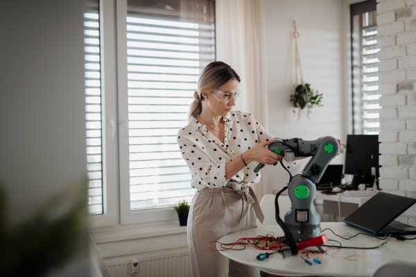 Woman engineer working on robotic arm project at home as part of STEM activity.