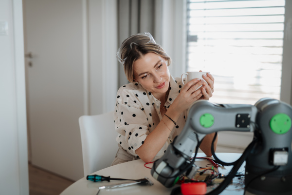 Female engineer building and programming a robotic arm at home. Robotics concept.