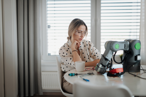 Woman engineer working on robotic arm project at home as part of STEM activity.