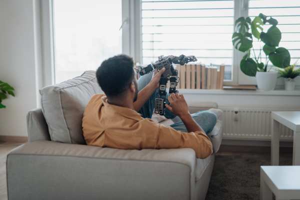 Handsome man holding small robot and lying on a sofa.