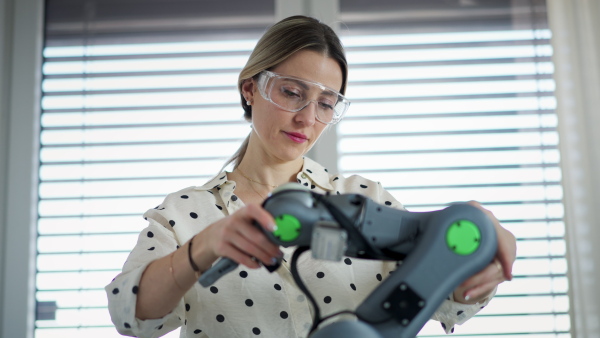 Female engineer building and programming a robotic arm at home. Robotics concept.