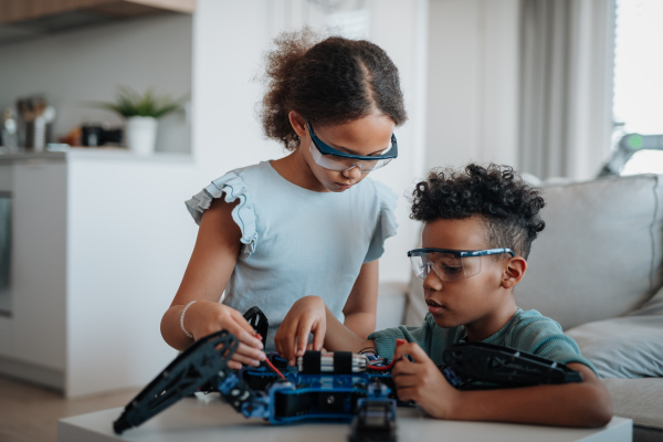 Kids building their first homemade robot at home. Educational robotic kit for children.