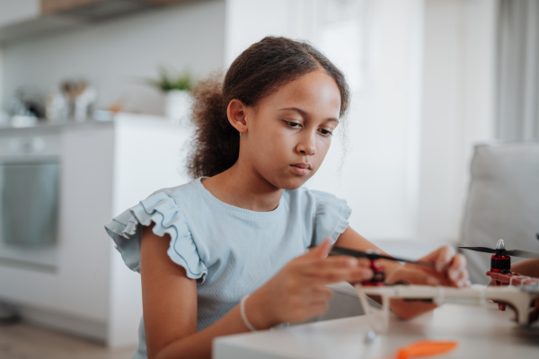 Focused girl working on small robot toy at home as part of STEM learning.