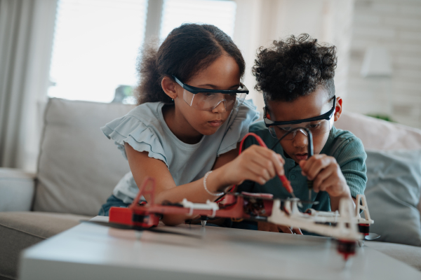 Kids building their first homemade robot at home. Educational robotic kit for children.