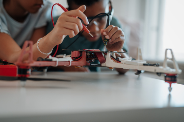 Classmates assembling robotic kit and working with circuit board at home.