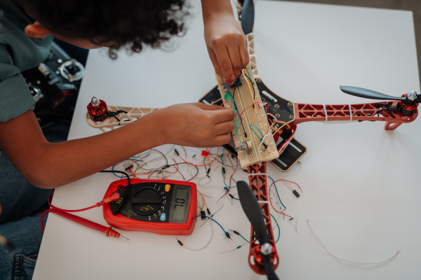 Young schoolboy assembling robotic kit and working with circuit board at home.
