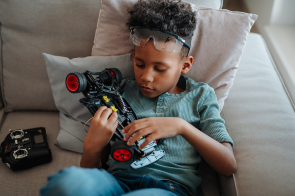 Focused boy building and programming robot car at home as part of STEM learning.