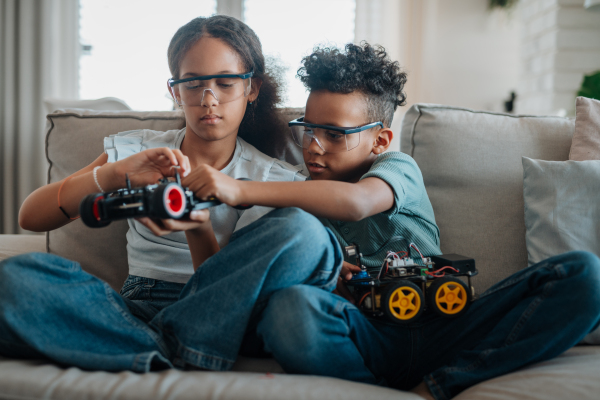 Siblings building and programming robot car at home as part of STEM learning.