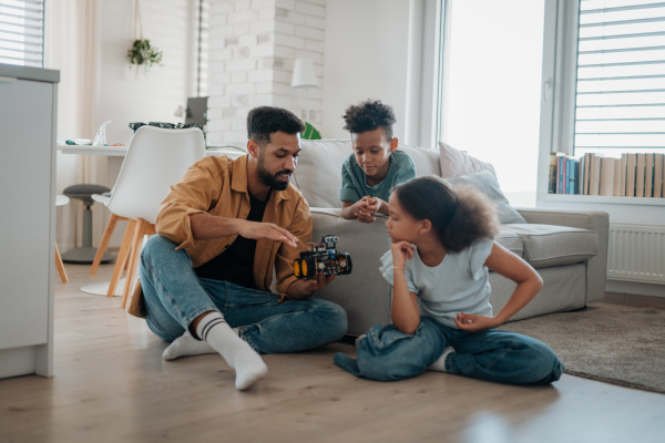 Father teaching kids about STEM, robotics, and discussing technology at home.