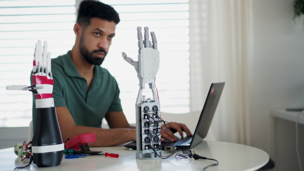 Young engineer building and programming a robotic arm at home. Robotics concept.