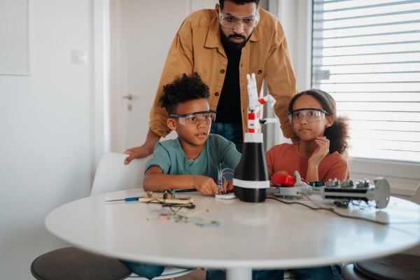 Father teaching kids about STEM, robotics, and discussing technology at home.