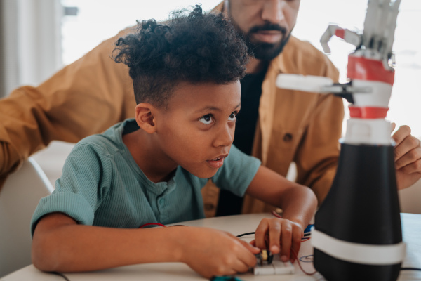 Father and son working on robotic car together. STEM and technology concept.