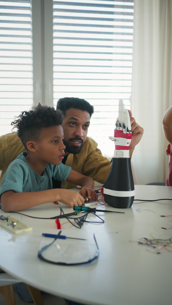 Father teaching kids about STEM, robotics, and discussing technology at home.