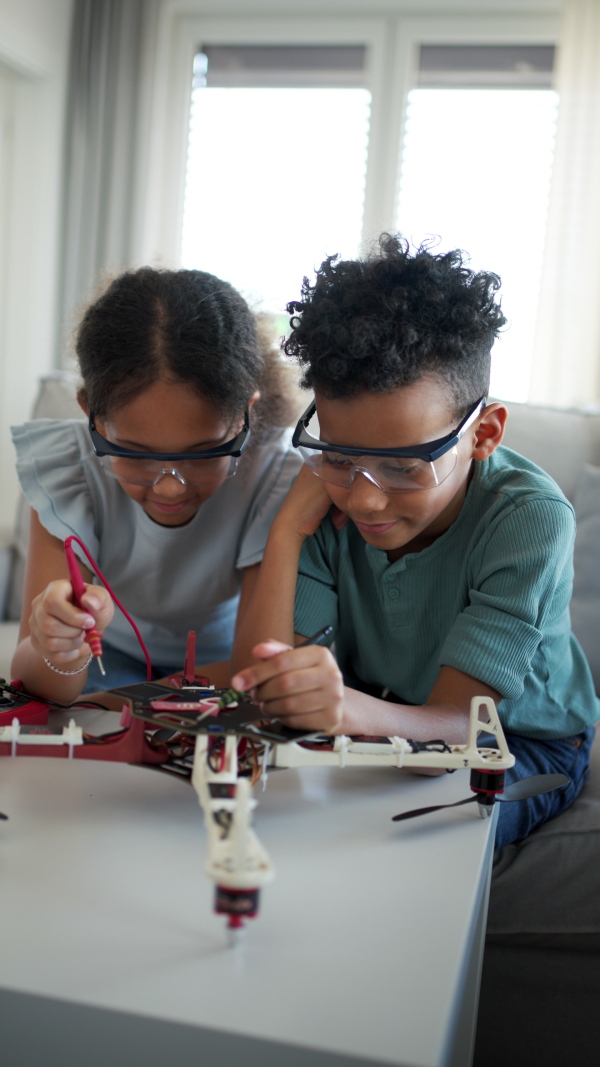 Kids building their first homemade robot at home. Educational robotic kit for children.