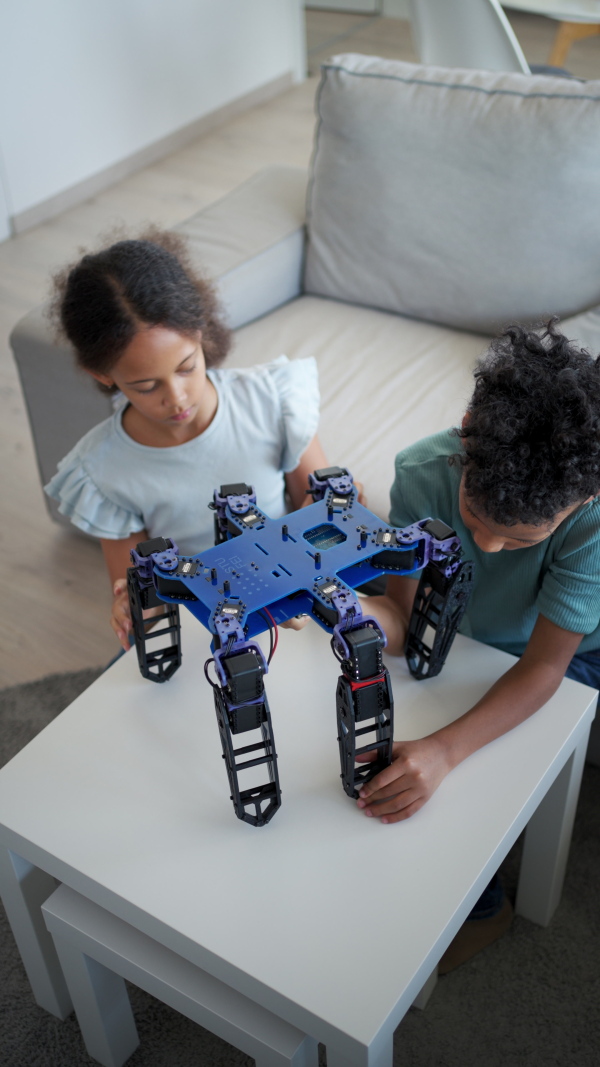 Kids building their first homemade robot at home. Educational robotic kit for children.