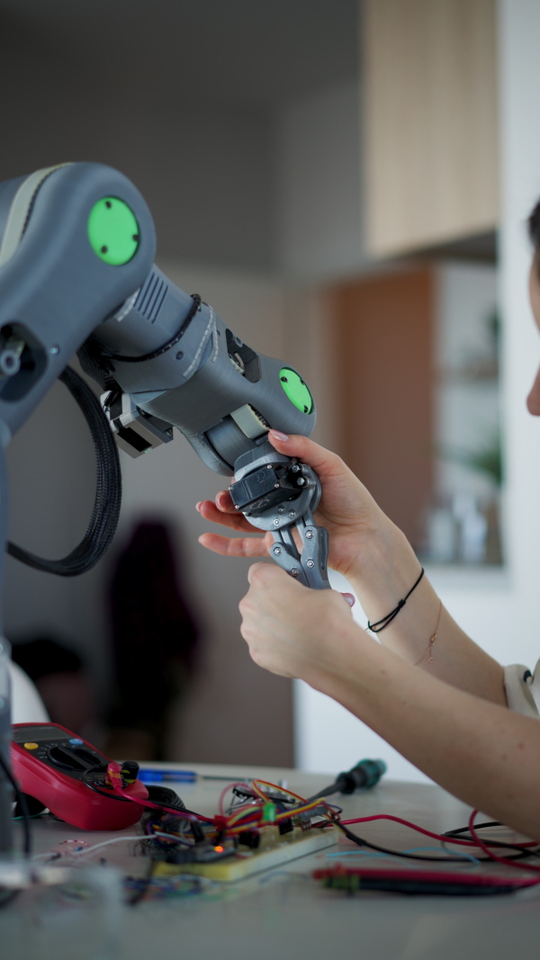 Close up of a female engineer building and programming a robotic arm at home. Robotics concept.