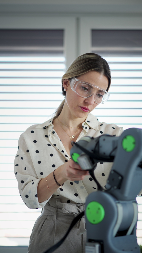 Female engineer building and programming a robotic arm at home. Robotics concept.