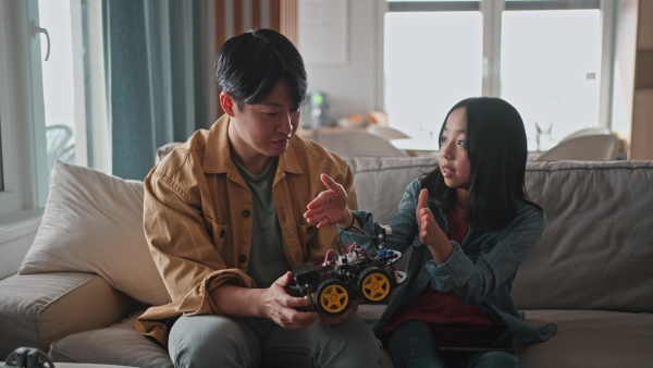 Father teaching his curious daughter about STEM, robotics, and discussing technology.