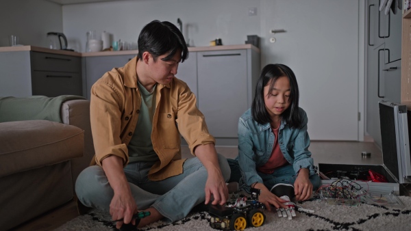 Father teaching his curious daughter about STEM, robotics, and discussing technology.