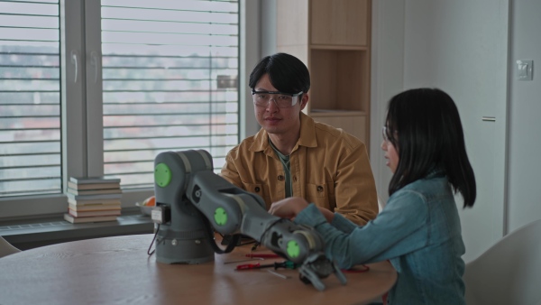 Father teaching his curious daughter about STEM, robotics, and discussing technology.
