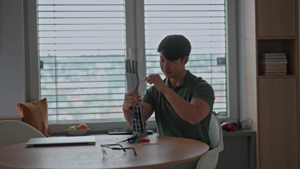 Young engineer building and programming a robotic arm at home. Robotics concept.