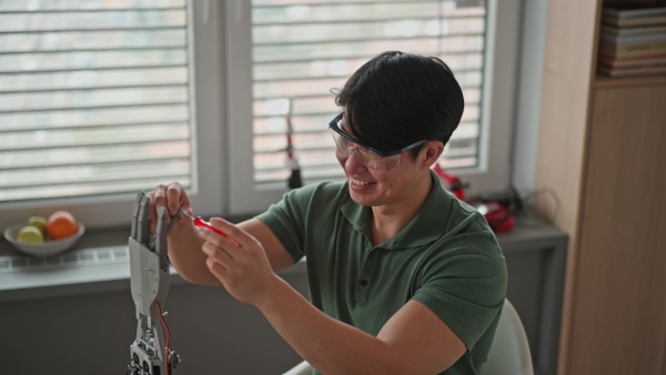 Young engineer building and programming a robotic arm at home. Robotics concept.